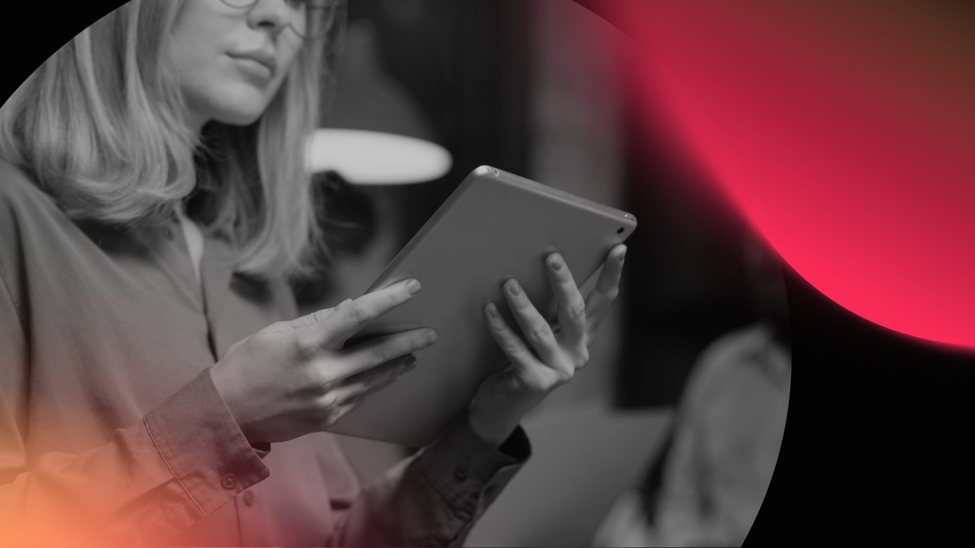 A person with shoulder-length hair and glasses holds and looks at a tablet. The image is mostly black and white, featuring abstract red and orange light effects in the corners, evoking creativity—perfect for a web design agency.