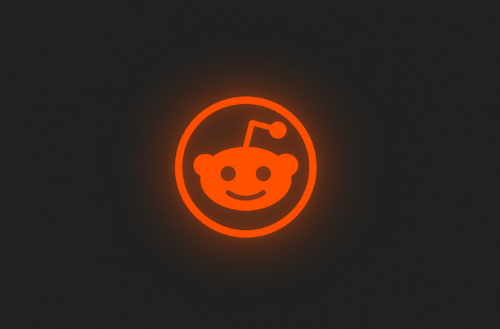 The glowing orange Reddit logo, featuring a smiling alien face with an antenna, is centered on a dark background—perfect for AI SEO enthusiasts seeking inspiration.