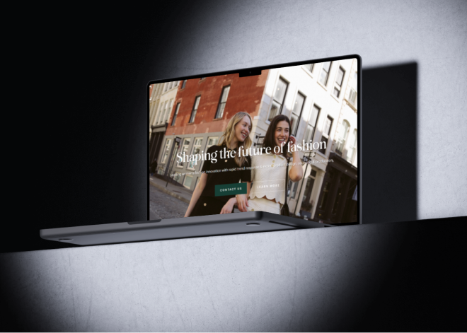 A laptop on a gray surface displays a website featuring two smiling women walking on a city street, highlighting the impact of branding with the text “Shaping the future of fashion.”.